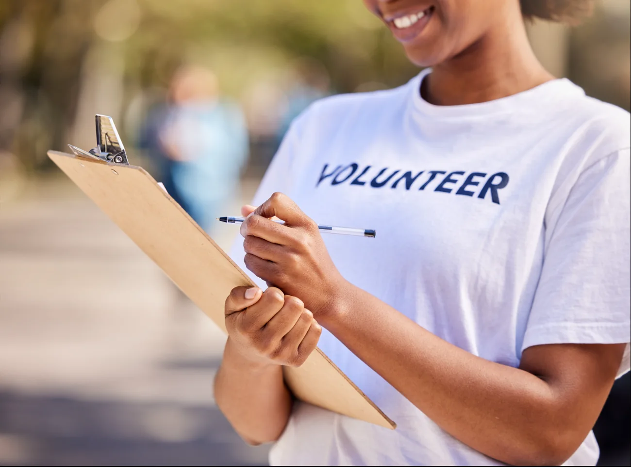 A volunteer in a Volunteer t-shirt holding a clipboard