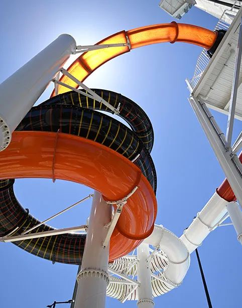 Looking up at an orange and black waterslide against a blue sky