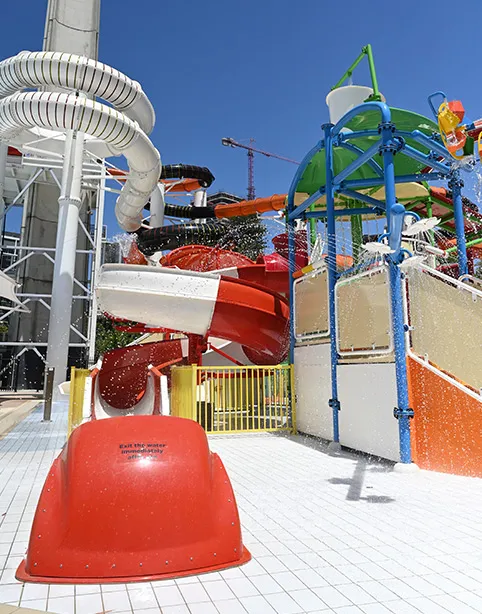 A red slide and splash park tower on a sunny day